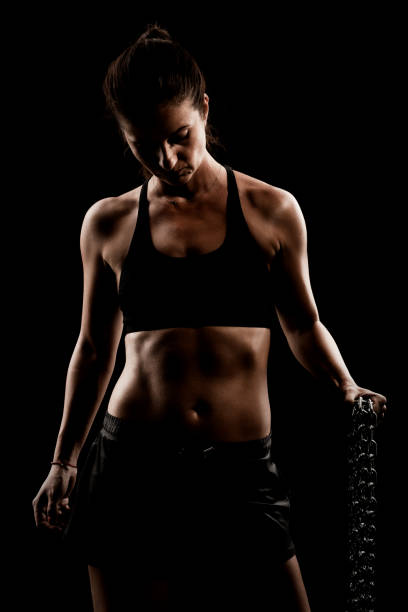 istock Strong fit girl with metal chain. Pulling and posing against black background.. 1389211395