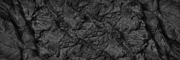 istock Black white rock texture. Dark gray stone wall background with space for design. Cracked rough mountain surface. Close-up. Wide banner. Panoramic. 1389213487