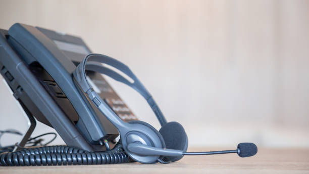 istock Communication support, call center and customer service help desk. VOIP headset on telephone keyboard. 1389214660