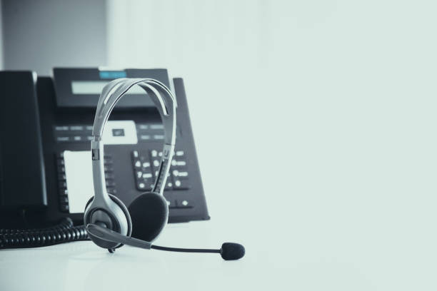 istock Communication support, call center and customer service help desk. VOIP headset on telephone keyboard. 1389219209
