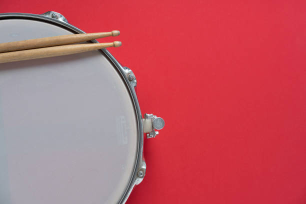 istock Drum stick and drum on red table background, top view, music concept 1389228372