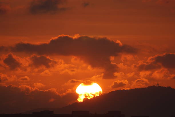 istock Bright and Hot sun rising through the mountain setting the sky in deep orange 1389233433