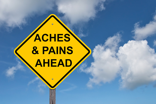 Aches & Pains Ahead Caution Sign - Blue Sky Background