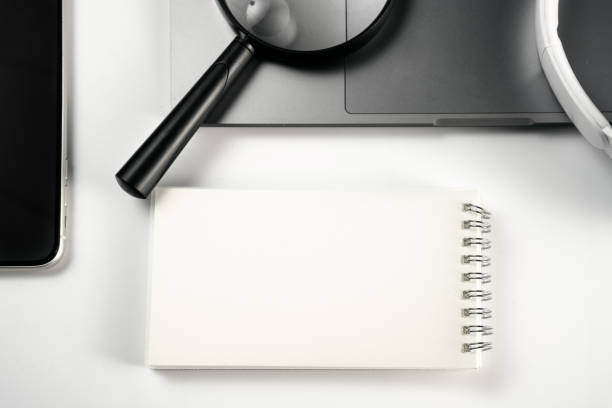istock Computer, magnifying glass, glasses, headphones and mobile phone on white background board 1389235303