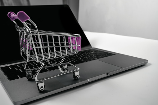 Computer and shopping cart on white background board