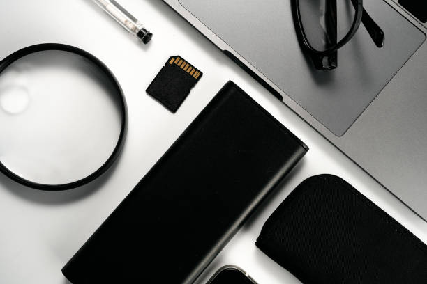 Business concept. Flat lay composition with various black gadgets. Computer keyboard, smartphone, leather wallet, glasses on dark black surface. Business people items. Top view.