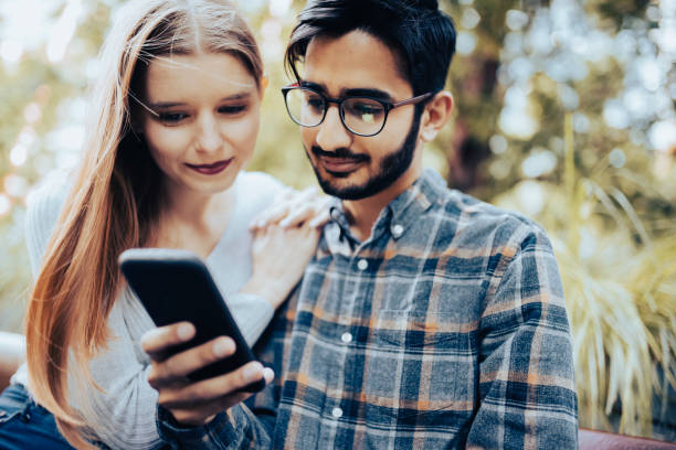 istock Young couple having fun with a smartphone in park 1389241201