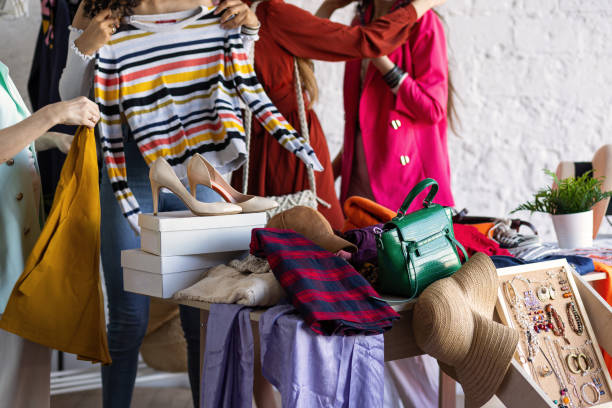スワップホームパーティーでの若い女性 - 服、靴、バッグ、友人間のジュエリー交換。ゼロウェイストショッピング、環境にやさしいコンセプト、持続可能なライフスタイル。大学生活。 - bazaar ストックフォトと画像