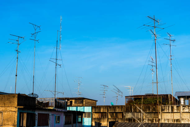 alter stil fernsehen (tv) antenne und satellit auf dem dach mit dem haus oder gebäude in provinziellem bereich in blauem himmel mit wolkenhintergrund in thailand, analoge tv-empfänger-panels - television aerial roof antenna city stock-fotos und bilder