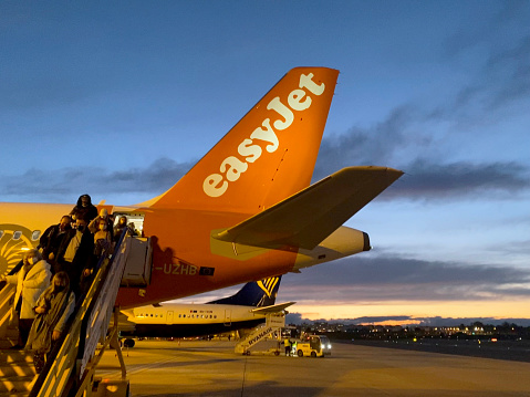 Passengers disembarking on steps from rear door of Easyjet Airbus 320 after landing at Lisbon Airport.