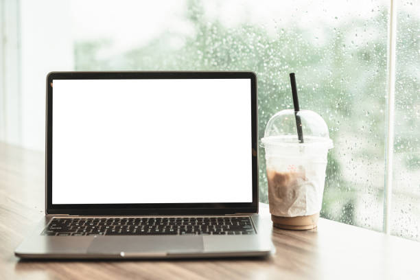 istock Mockup of laptop computer with empty screen with coffee isolate on wooden office desk in coffee shop like the background ,White screen 1389243039