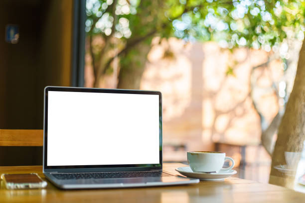 istock Mockup of laptop computer with empty screen with coffee cup and smartphone on table of the coffee shop background,White screen 1389243057