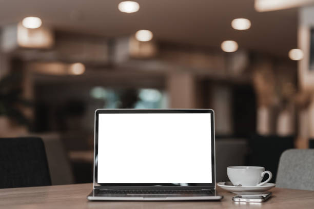 istock Mockup of laptop computer with empty screen with coffee cup and smartphone on table of the coffee shop background,White screen 1389243781