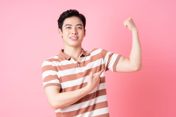 Young Asian man posing on pink background