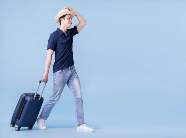 image d’un jeune homme asiatique tenant une valise sur fond bleu, concept de voyage - luggage hold photos et images de collection