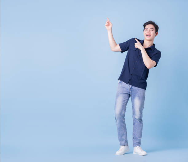 istock Full length image of young Asian man posing on blue background 1389246615