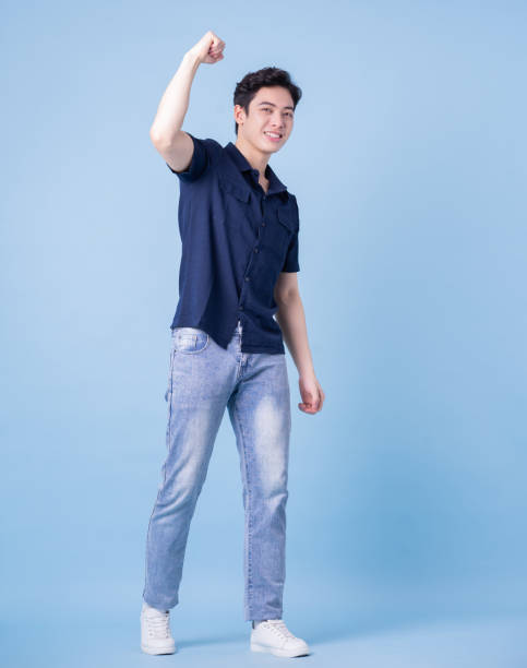 Full length image of young Asian man posing on blue background