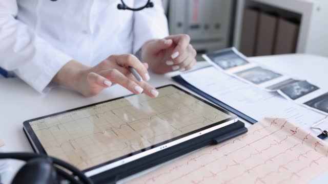 Cardiologist examines electrocardiogram of patient heart on tablet