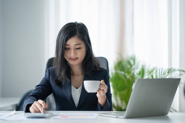 istock Businesswoman working on laptop while drinking coffee in the office 1389251665