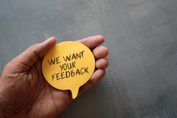 istock Hand holding yellow speech bubble with text WE WANT YOUR FEEDBACK 1389258386