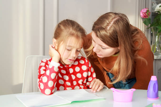 istock little girl doing homework sitting at kitchen table, learning at home. 1389263444