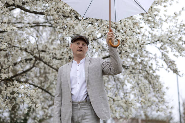 白い開花するマグノリアの中で傘をさした美しい笑顔の男 - magnolia flower single flower white ストックフォトと画像