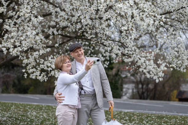 ein verliebtes paar macht ein selfie-foto vor dem hintergrund einer weiß blühenden magnolie - 45 hochzeitstag stock-fotos und bilder