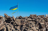 Krieg in der Ukraine. Zerstörtes ukrainisches Gebäude und beschädigte Flagge im Wind.