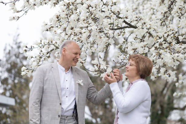 ein verliebtes paar genießt den frühling in der nähe einer weiß blühenden magnolie - 45 hochzeitstag stock-fotos und bilder