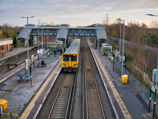 vías férreas y plataformas en la estación de hooton en wirral, en el noroeste de inglaterra, reino unido. un solo tren de cercanías espera en la plataforma para que los viajeros bajen y aborden el tren. - northwest england fotografías e imágenes de stock