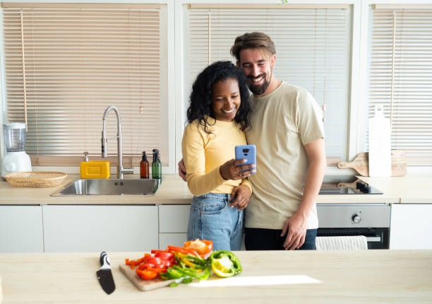 istock Smiling young multiethnic heterosexual couple looking at mobile phone 1389273368