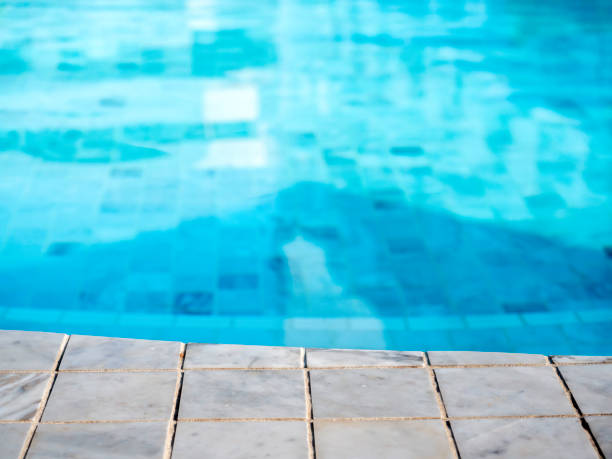 istock Summer pool background. Empty space on the pool edge, marble stone tiles and blurred swimming pool in tropical resort, summer background for display or montage your products. 1389274432