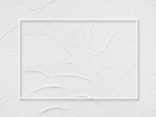 istock A minimalist white thin line makes a decorative square border frame on white wall with painted texture surface background, top view. 1389274498
