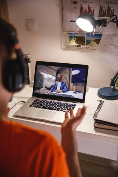 istock Over the shoulder view of young man gesturing while video chatting with a friend 1389274844