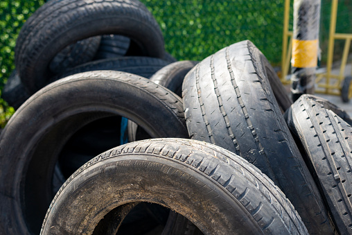 This is a full frame photo of a bunch of old tires stacked on top of one another taken outside in the late afternoon.