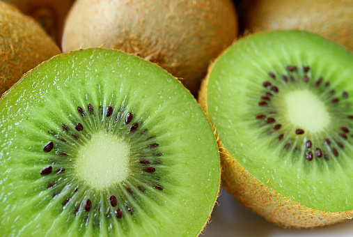 Closeup Two Halves of Fresh Ripe Kiwi Fruit with Whole Fruit in the Backdrop