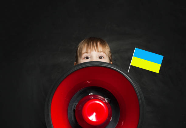 niño pequeño con altavoz y bandera ucraniana sobre fondo negro. concepto de no guerra en ucrania - ukrainian culture audio fotografías e imágenes de stock