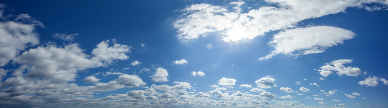 Day sky with sun behind white clouds