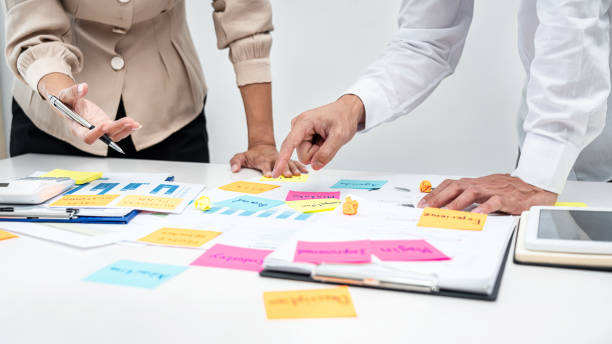 istock Two business people pointing keyword in post it notes on the table during brainstorming about new business project 1389283633