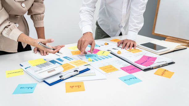 istock Two business people pointing keyword in post it notes on the table during brainstorming about new business project 1389283634