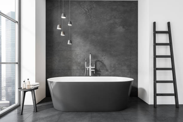 istock Modern bathroom interior with gray ceramic bathtub. Gray tiled walls and flooring. Panoramic window. Ladder. No people. 3d rendering. 1389285140