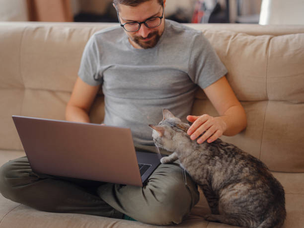 istock Working at home with pet. Man works from home typing on laptop. 1389285819