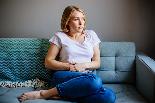 Mujer que experimenta dolor de estómago mientras está acostada en el sofá de su casa photo