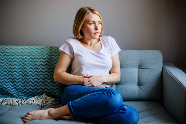 femme souffrant de douleurs à l’estomac allongée sur le canapé à la maison - uncomfortable photos et images de collection