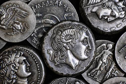 Ancient Greek coin with Alexander the Great portrait, pile of silver tetradrachm coins. Top view of old rare money. Concept of Greece, valuable coins collection, ancient history and treasure.