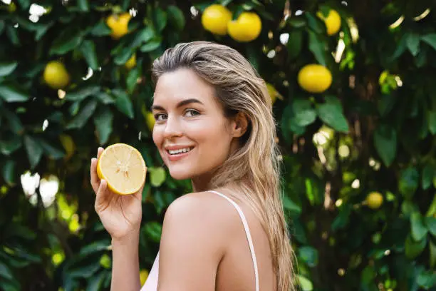 Outdoor portrait of beautiful woman with smooth skin with a lemon fruit in her hands