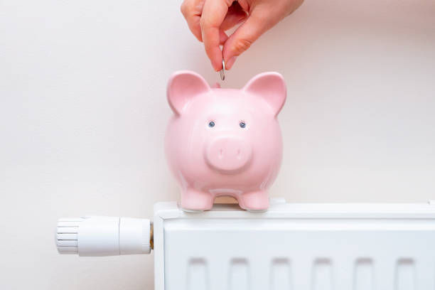 Piggy bank on radiator. Heating cost concept stock photo