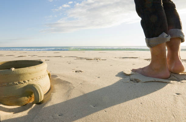 Male feet in hiking shoes on sandy beach. Summertime.