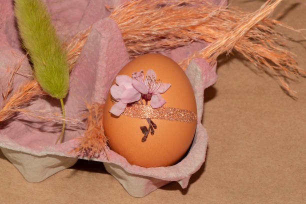 Easter eggs of natural color with painted tiny flowers on them in a basket with dried flowers. Creative easy idea of decorating eggs. Neutral colors, aesthetics. Selective focus.