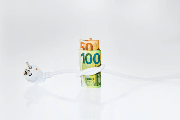 Roll of Euro banknotes tied with an electrical plug on light background. Concept of saving electricity at home. Electricity cost and expensive energy concept. Electricity consumption stock photo